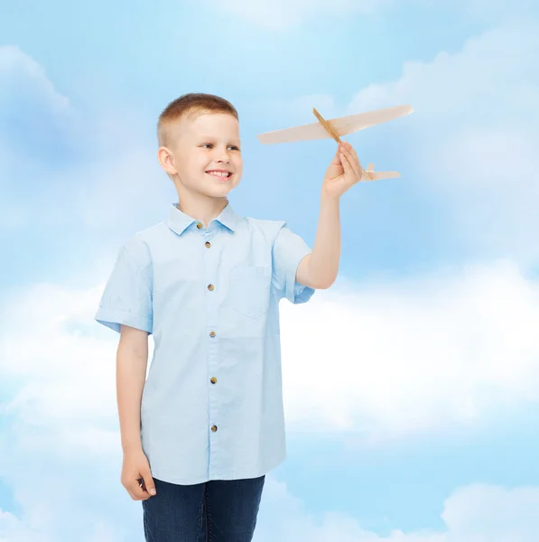 Niño sonriente sosteniendo un modelo de avión de madera — Foto de Stock