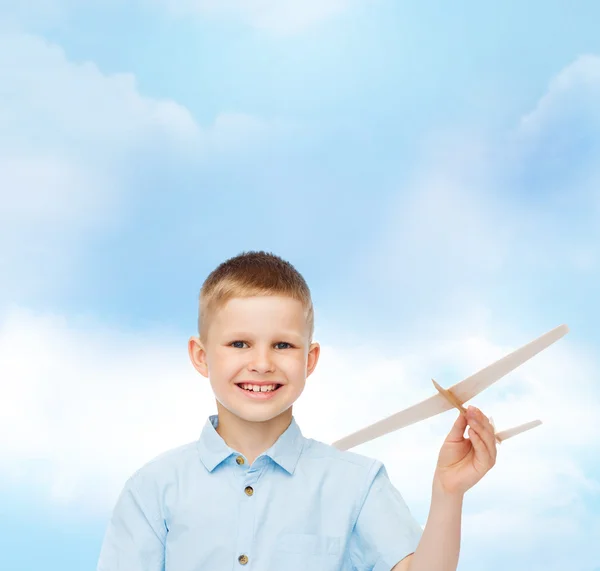 微笑的小男孩抱着一个木制飞机模型 — 图库照片