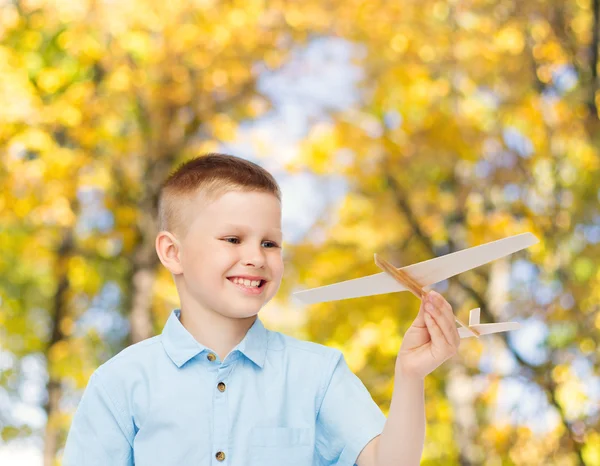Menino sorrindo segurando um modelo de avião de madeira — Fotografia de Stock