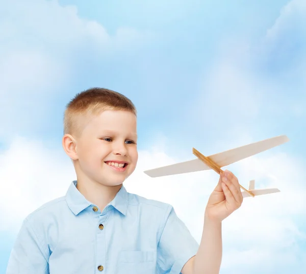 Niño sonriente sosteniendo un modelo de avión de madera — Foto de Stock