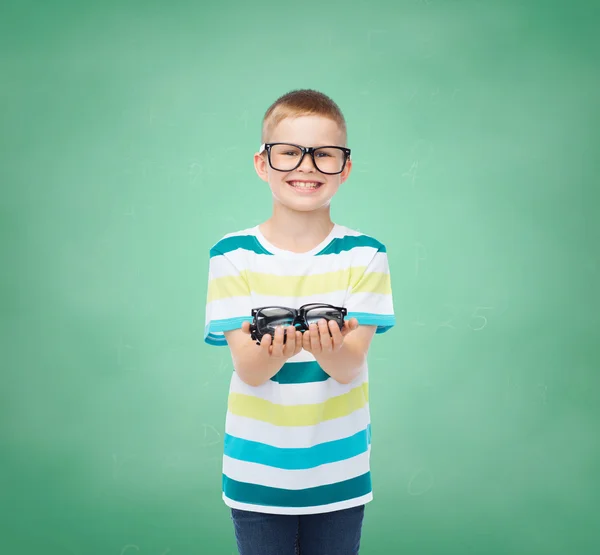 Улыбающийся мальчик в очках, держащий очки — стоковое фото