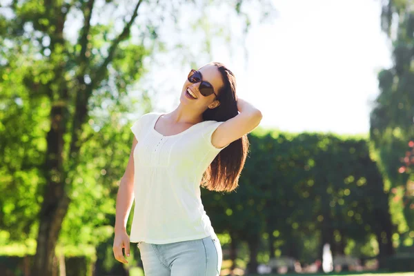 Усміхнена молода жінка в сонцезахисних окулярах в парку — стокове фото