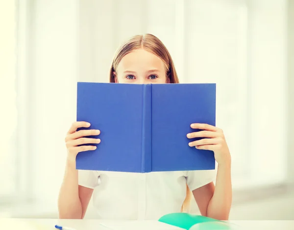 Girl studying and reading book at school — Stock Photo, Image