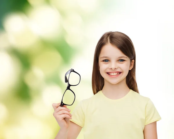 Sorrindo bonito menina segurando óculos pretos — Fotografia de Stock