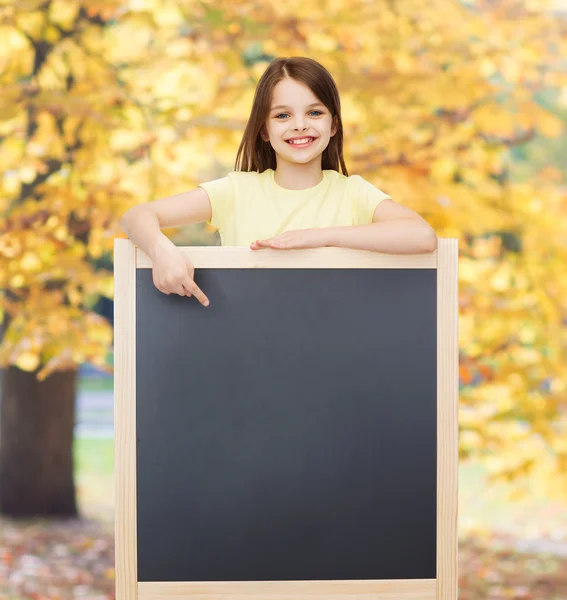 Szczęśliwy mała dziewczynka palcem wskazującym do tablicy — Zdjęcie stockowe
