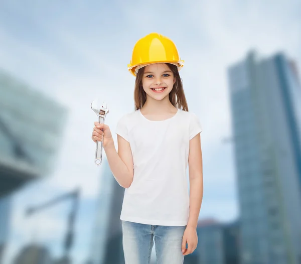 Leende liten flicka i hardhat med skiftnyckel — Stockfoto