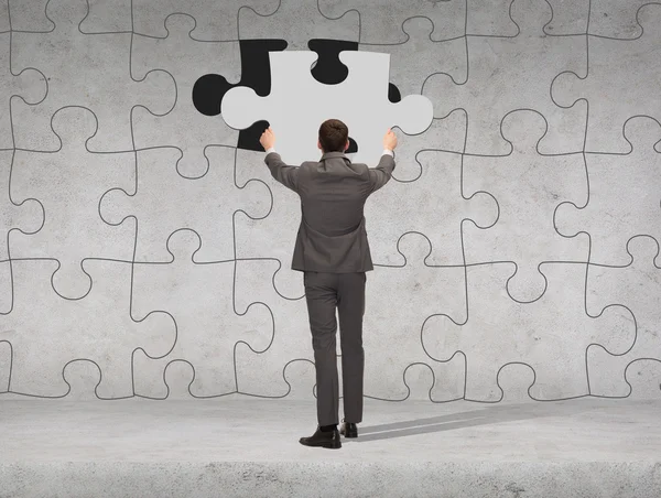 Businessman in suit setting piece of puzzle — Stock Photo, Image