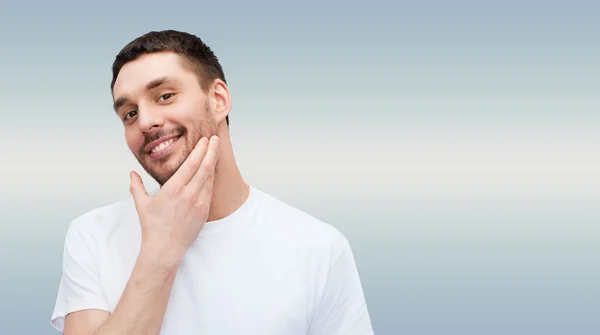 Bonito homem sorridente tocando seu rosto — Fotografia de Stock