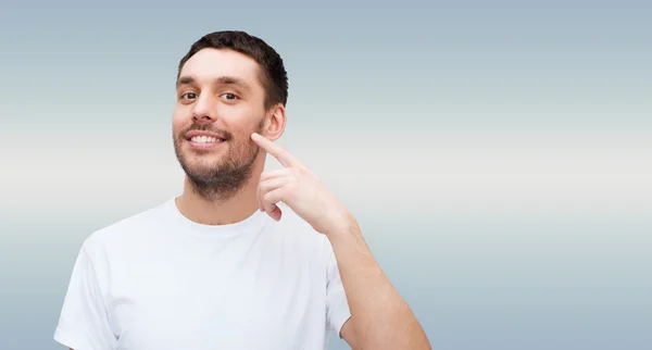 Sorrindo jovem bonito homem apontando para bochecha — Fotografia de Stock