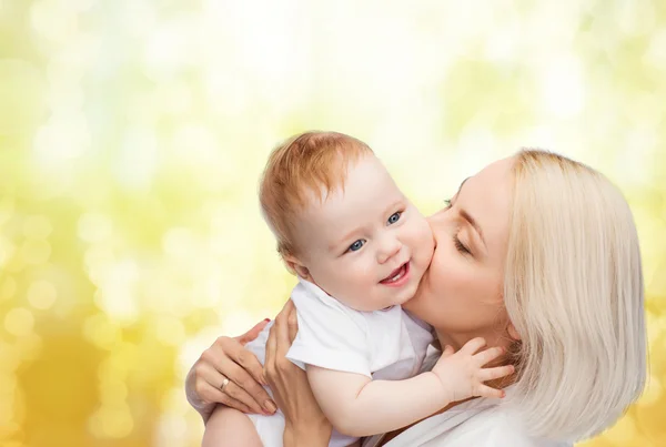 Glückliche Mutter küsst lächelndes Baby — Stockfoto