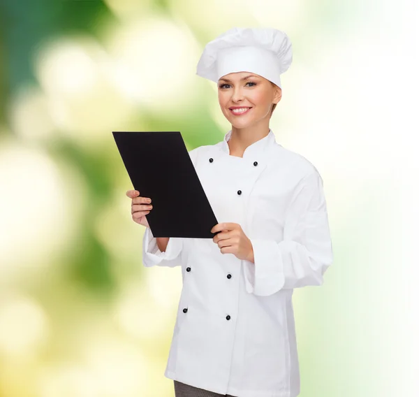 Lachende vrouwelijke chef-kok met zwarte blanco papier — Stockfoto