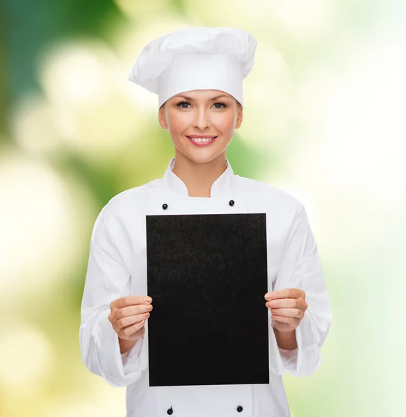 Lachende vrouwelijke chef-kok met zwarte blanco papier — Stockfoto