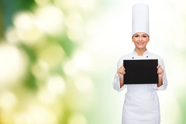 Lachende vrouwelijke chef-kok met zwarte blanco papier — Stockfoto