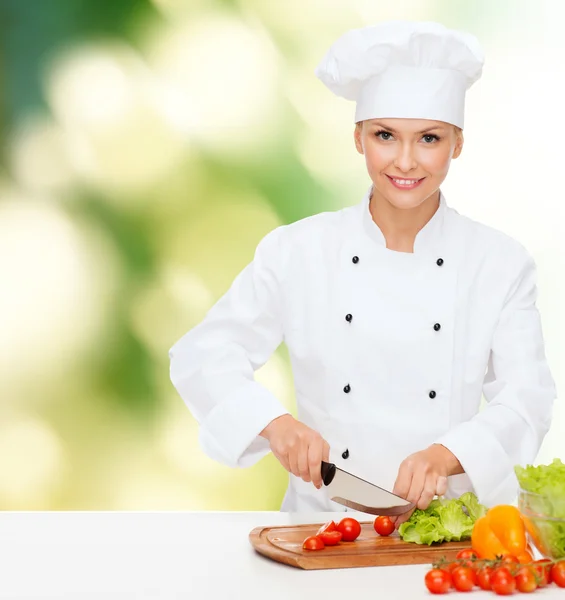 Sorridente chef feminino cortar legumes — Fotografia de Stock