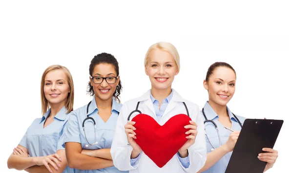 Doctora y enfermeras sonrientes con corazón rojo — Foto de Stock