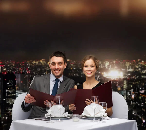 Smiling couple with menus at restaurant — Stock Photo, Image