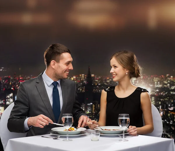 Casal sorrindo comer prato principal no restaurante — Fotografia de Stock