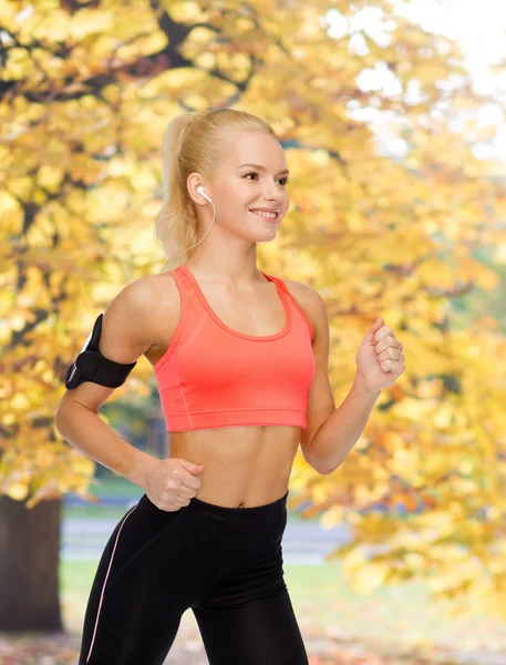 Mujer deportiva corriendo con smartphone y auriculares — Foto de Stock