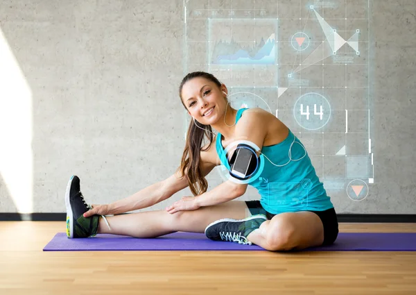 Leende kvinna sträcker benet på matta i gym — Stockfoto