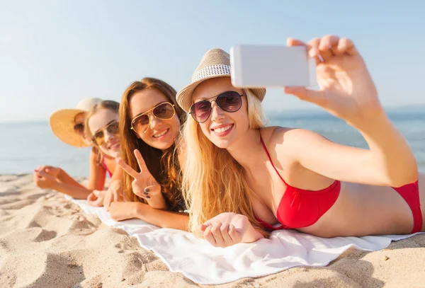 Grupo de mujeres sonrientes con teléfono inteligente en la playa — Foto de Stock