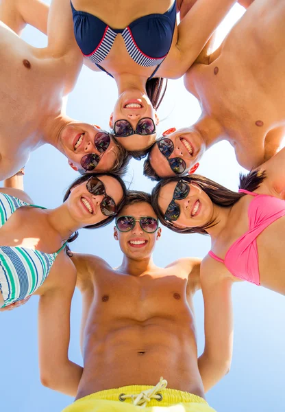 Smiling friends in circle on summer beach — Stock Photo, Image