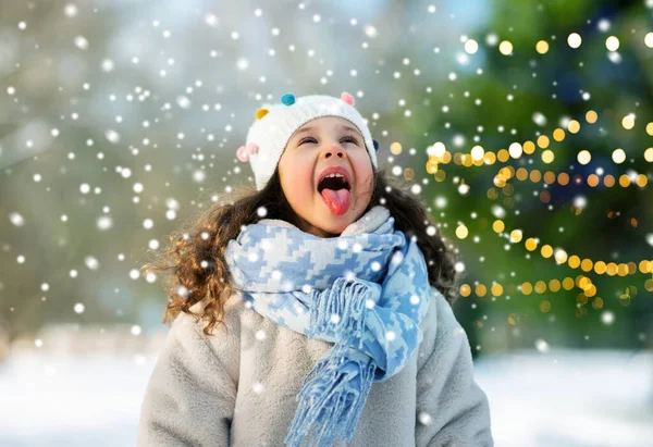 Gelukkig meisje vangen sneeuw door haar tong in de winter — Stockfoto