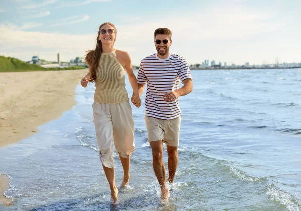 快乐的夫妻在夏天的海滩上奔跑 — 图库照片