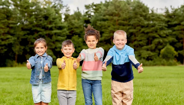 Glückliche Kinder zeigen Daumen hoch im Park — Stockfoto