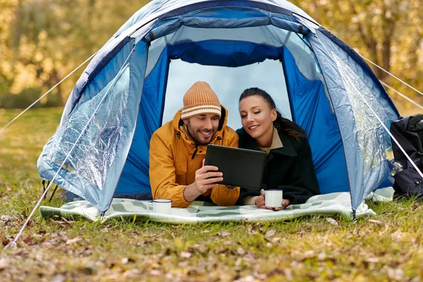 Пара с планшетным ПК пить чай в палатке — стоковое фото