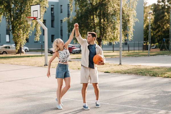 Casal feliz com bola no campo de jogos de basquete — Fotografia de Stock