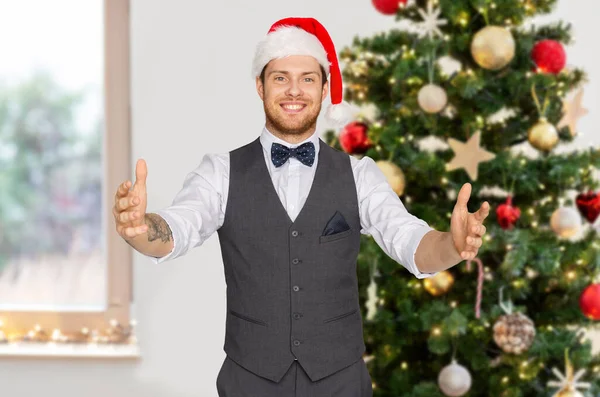 Glücklicher Mann mit Weihnachtsmütze, der etwas Fantasievolles in der Hand hält — Stockfoto