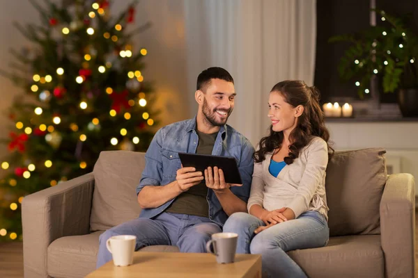 Счастливая пара с помощью планшетного ПК дома на Рождество — стоковое фото