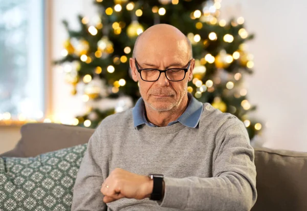 Hombre mayor mirando el reloj en casa en Navidad — Foto de Stock