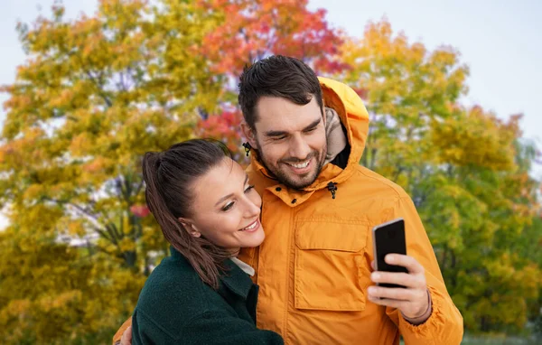 Coppia con smartphone su sfondo parco autunnale — Foto Stock