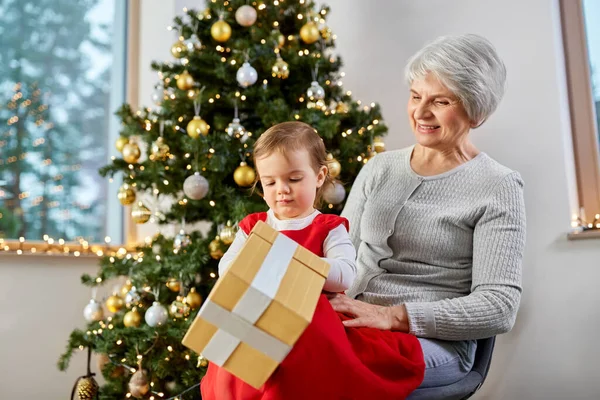 Mormor och liten flicka med julklapp — Stockfoto