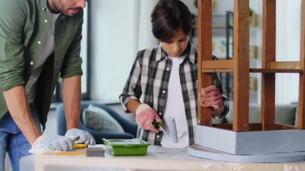 Baba ve oğul eski masayı gri renge boyuyorlar. — Stok video