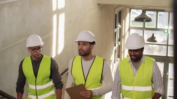 Архитекторы в шлемах, идущие наверх в офис — стоковое видео
