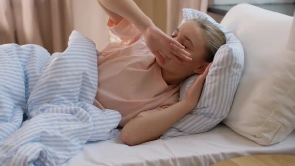 Schläfriges Mädchen wacht auf und dehnt sich zu Hause im Bett — Stockvideo