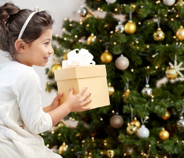 Glad liten flicka med gåva över julgran — Stockfoto