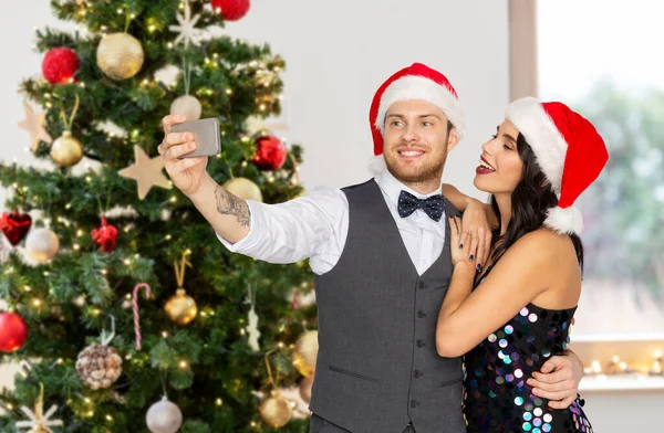 Casal em santa chapéus tomar selfie no Natal — Fotografia de Stock