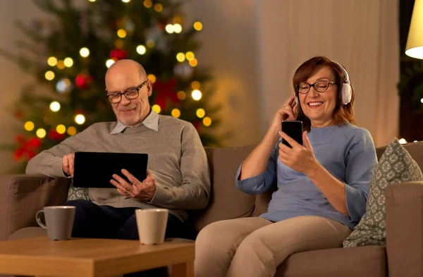 Senior paar met gadgets thuis op kerst — Stockfoto