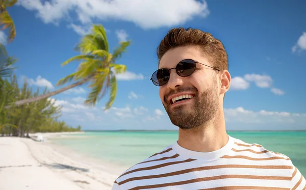 Молодой человек в солнечных очках над экзотическим пляжем — стоковое фото