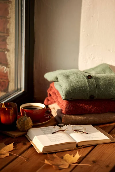 Könyv, kávé és őszi pulóverek ablakpárkányon — Stock Fotó