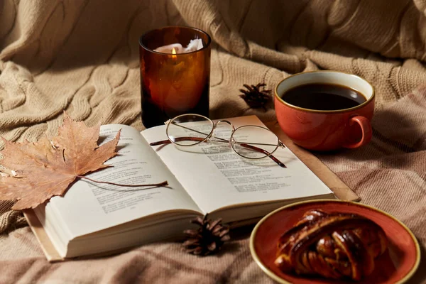 Kniha, skořicová buchta, káva a svíčka na podzim — Stock fotografie