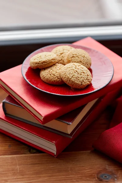 Sušenky na talíři a knihy na parapetu doma — Stock fotografie