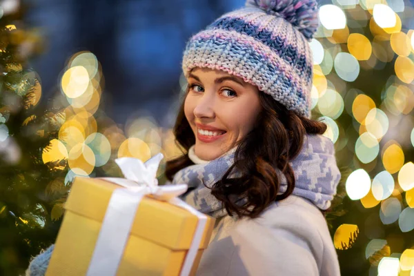 Szczęśliwa kobieta z prezentem świątecznym nad światłami — Zdjęcie stockowe