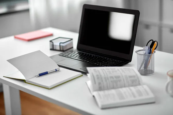 Ноутбук, блокнот і книга на столі в домашньому офісі — стокове фото