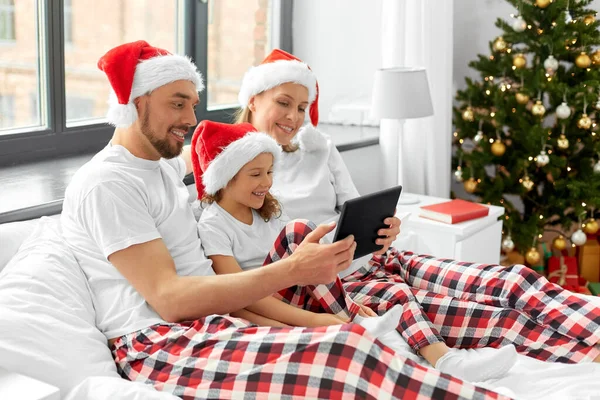 Šťastná rodina s tabletem PC v posteli na Vánoce — Stock fotografie