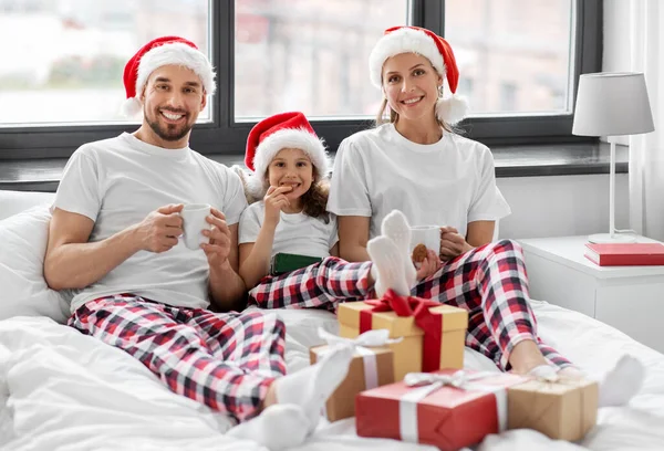 Mutlu aile Noel 'de yatakta kurabiye yiyor. — Stok fotoğraf