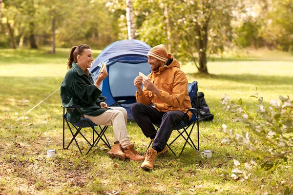 Casal feliz comer sanduíches no acampamento tenda — Fotografia de Stock